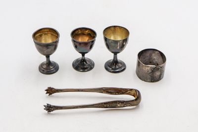 trois tasses en argent et deux cuillères posées sur un plateau blanc