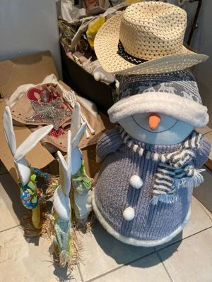 un bonhomme de neige portant un bonnet et une écharpe, à côté d'une valise