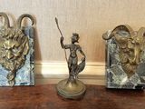 trois statues représentant un homme et une chèvre, posées sur une table