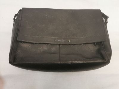 une photo d'un sac à main noir posé sur une table blanche