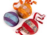 three different colored balls with ribbons and bows on a white surface