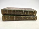 two old books are stacked on top of each other on a table