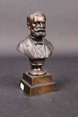 un buste en bronze représentant un homme barbu portant un nœud papillon