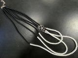 a close up of a black and white beaded necklace on a black surface