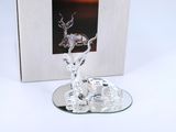 a glass deer figurine on a plate with a picture in the background