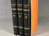 two black books with gold trims are sitting on a gray surface