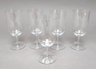 four empty wine glasses are lined up on a white surface