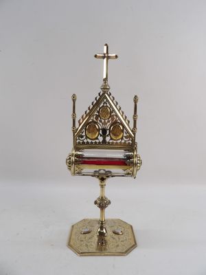 un coffret richement décoré, doré et rouge, surmonté d'une croix