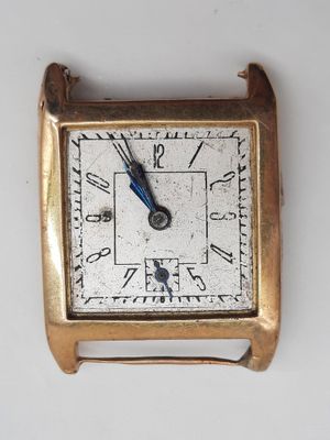 une petite montre carrée en or avec une trotteuse bleue