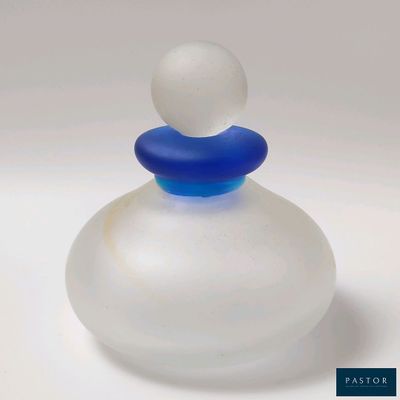 une petite bouteille en verre avec un bouchon bleu posée sur une surface blanche