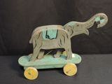 a small wooden elephant on a skateboard on a black background