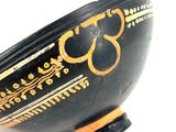 a black bowl with gold designs on it on a white surface