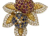 un gros plan sur une broche en forme de fleur sertie de diamants et de saphirs