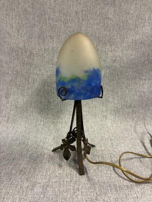 une lampe à l'ancienne, avec un abat-jour bleu et blanc, posée sur un pied en métal