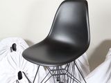 a black chair sitting on top of a bed covered in white sheets