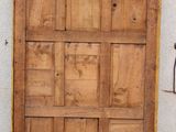a wooden door with a metal handle on the side of a building