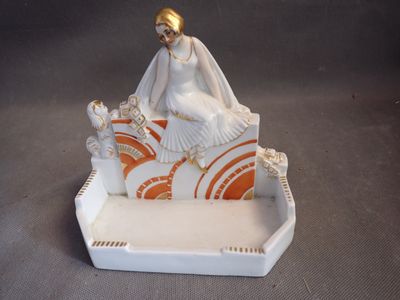 a figurine of a woman sitting on a bed