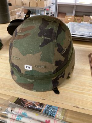 un casque de camouflage posé sur une table à côté d'une paire de ciseaux