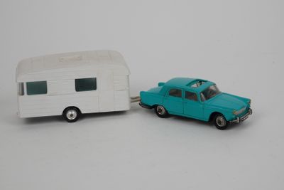 une petite voiture à côté d'une petite remorque, posées sur une surface blanche