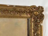 a picture of a gold framed mirror hanging on a wall