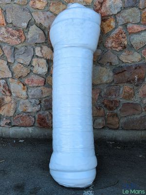 un grand vase blanc posé par terre près d'un mur de pierre