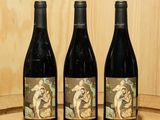trois bouteilles de vin posées sur un tonneau en bois