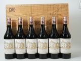 six bottles of red wine are lined up in front of a wooden crate