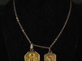 a gold necklace with two small medallions on a black mannequin