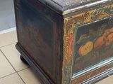 a wooden chest with a painting on it on a tile floor