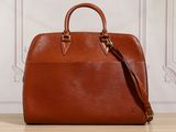 un sac Louis Vuitton marron posé sur une table en bois