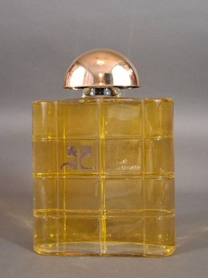 yellow perfume bottle with a silver lid on a gray surface