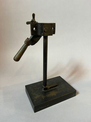 a small metal object on a stand on a white background