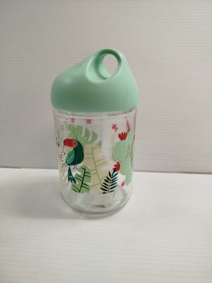 un verre avec un couvercle vert posé sur une table blanche