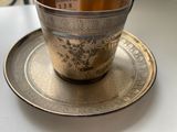 a silver cup and saucer on a silver plate