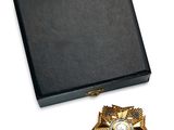 boîte noire ornée d'une broche dorée et blanche et d'une épingle à broche dorée