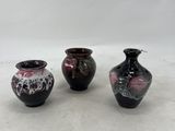 three small vases sitting on a white surface with a white background