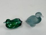 two glass ducks sitting next to each other on a table