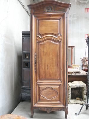 une grande armoire en bois, dans une pièce, à côté d'une chaise