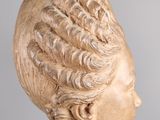 marble bust of a woman with curly hair on a pedestal