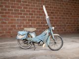 a small blue motorcycle parked in front of a brick wall