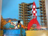 an image of a person holding up a book with a rocket in the background