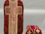 un tissu rouge et doré orné d'une croix, à côté d'une boîte rouge