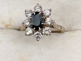 un gros plan d'une bague ornée d'un diamant noir entouré de diamants blancs