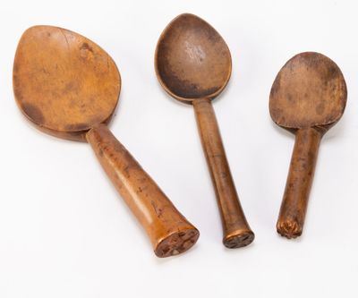three wooden spoons and a wooden spoon on a white surface