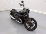 une moto noire garée dans une pièce aux murs blancs
