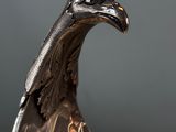 silver statue of a bird on a table with a gray background