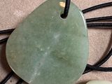 a green stone pendant with white stones on a black cord