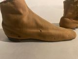 pair of brown leather boots with holes on them on a white surface