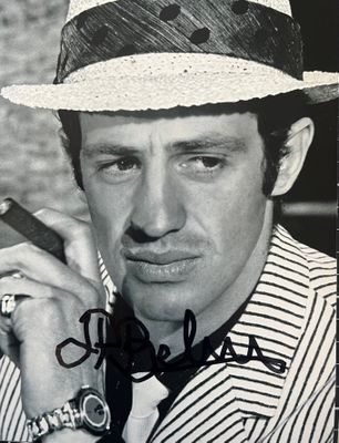 photographie en noir et blanc d'un homme coiffé d'un chapeau et fumant un cigare