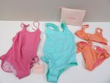 three swimsuits and a purse are on a table